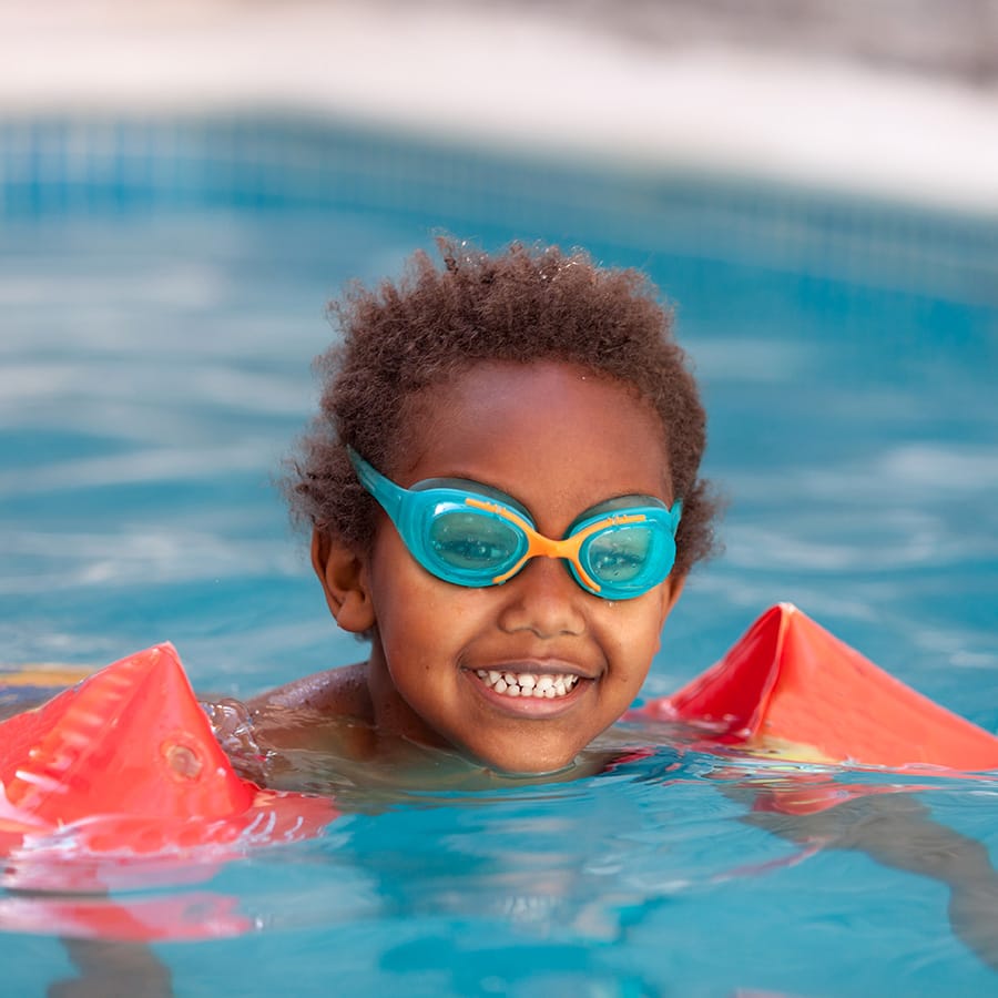 Young child with arm floats in a fiberglass swimming pool.
