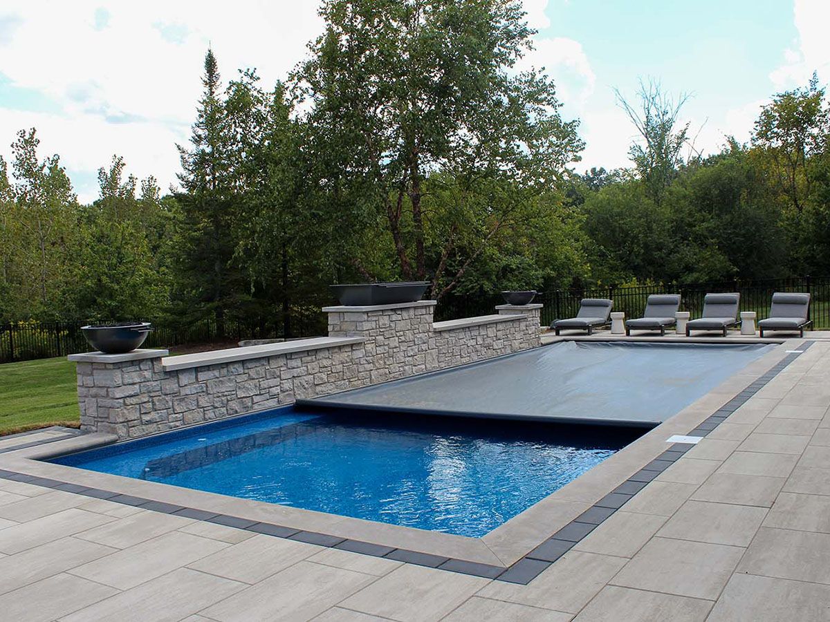 Rectangualr in-ground fiberglass pool with a half open automatic pool cover from Coverstar.
