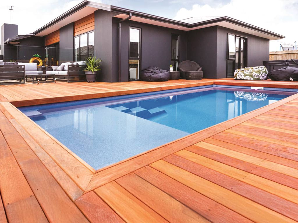 In-ground rectangular fiberglass pool from Latham Pools surrounded by a wooden deck.