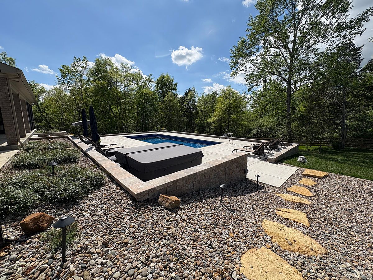 In-ground fiberglass pool area with retaining wall in Shelbyville, Kentucky.