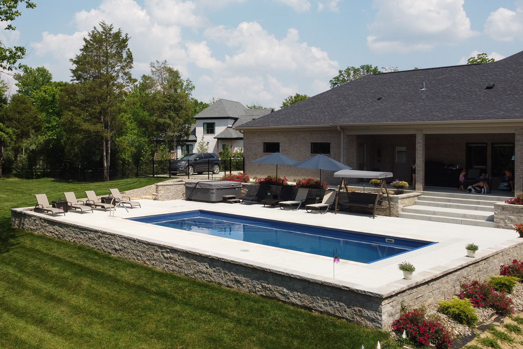 A rectangular fiberglass in-ground backyard pool in Crestwood, Kentucky with a retaining wall.