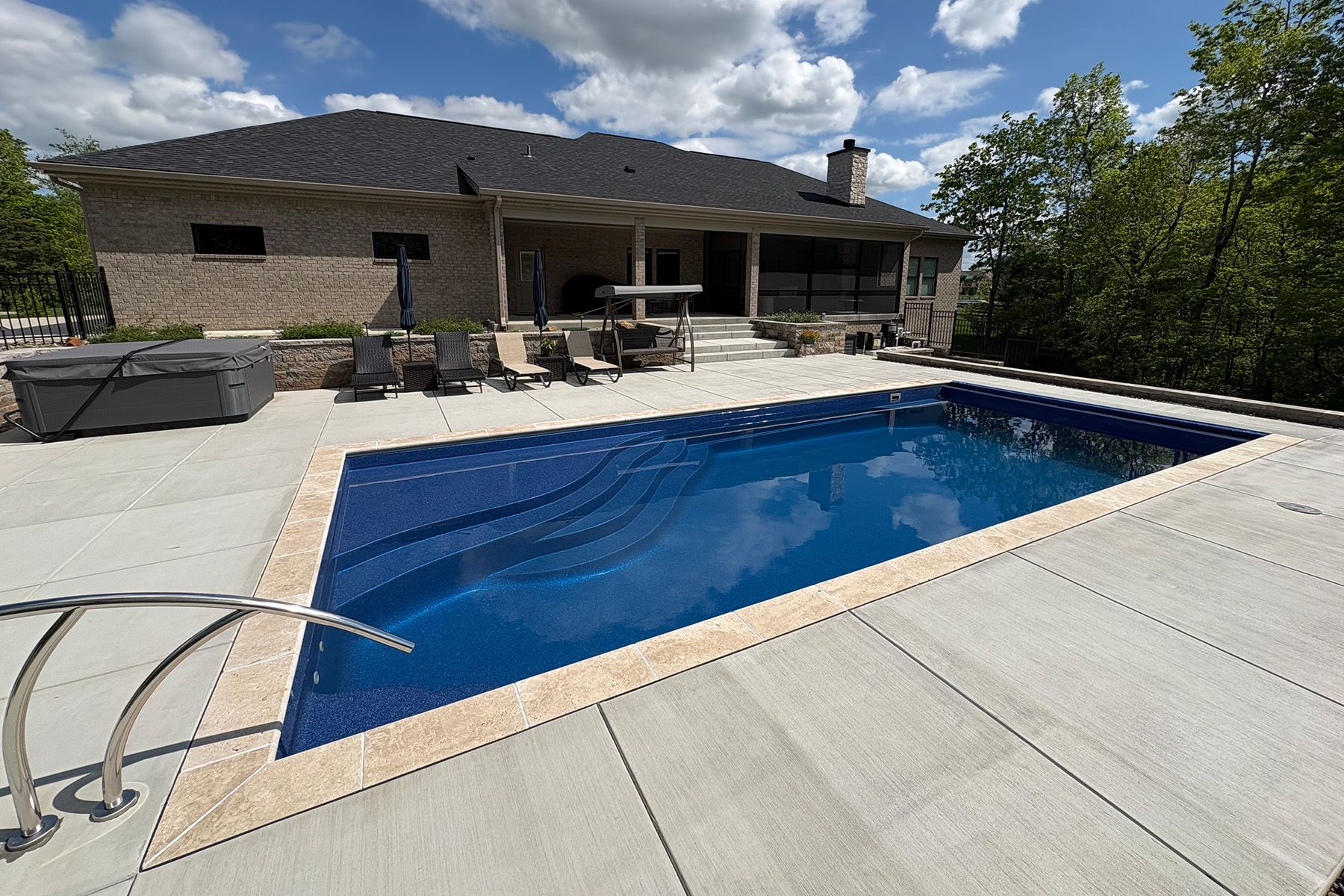 A rectangular fiberglass in-ground backyard pool in Crestwood, Kentucky with a retaining wall.