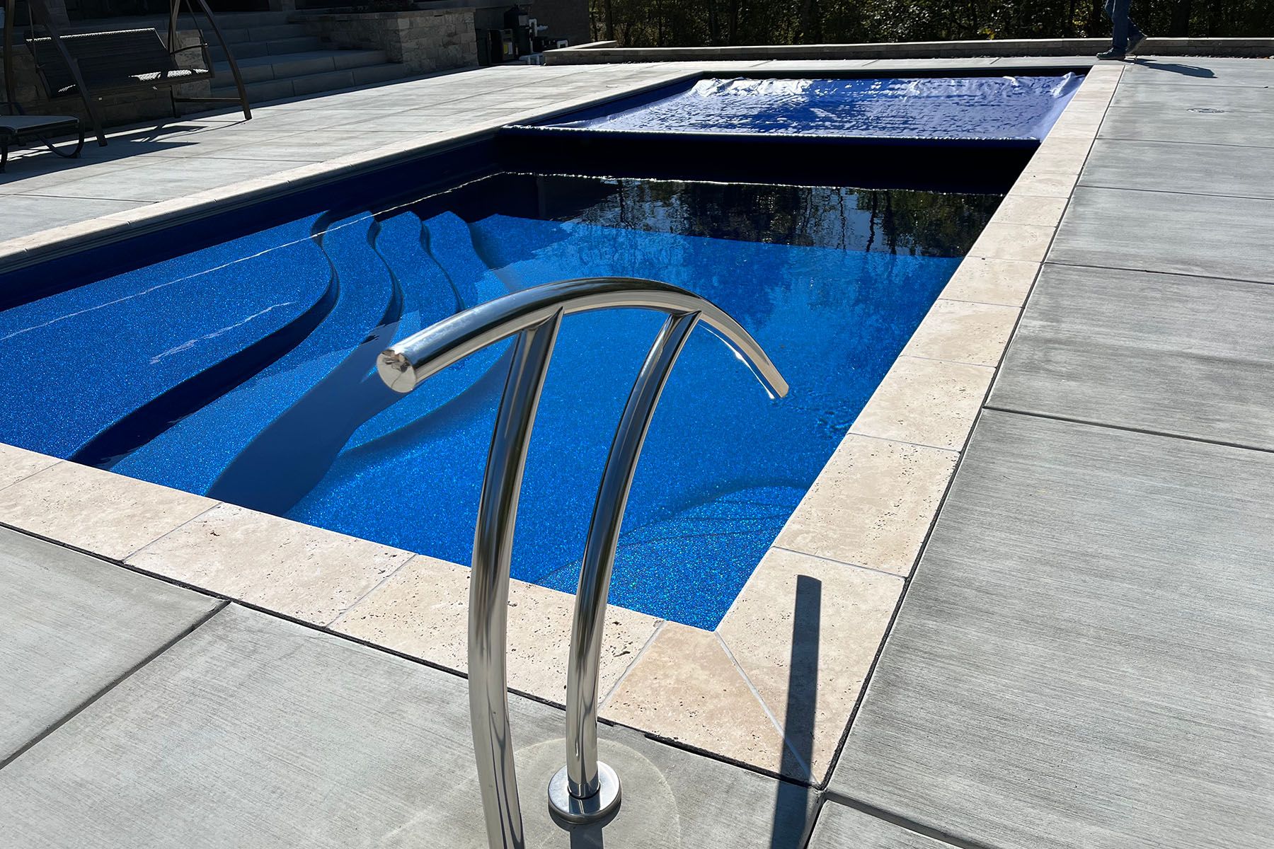 Close up of a rectangular fiberglass in-ground backyard pool in Crestwood, Kentucky with an automatic pool cover.