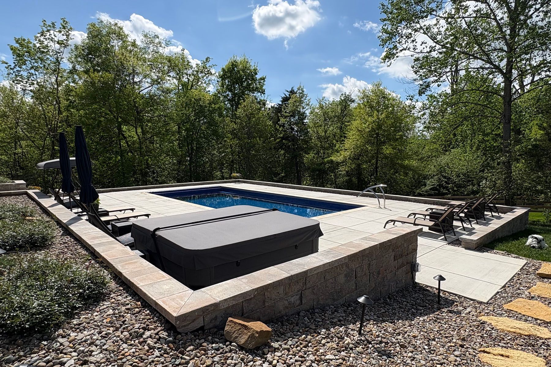 A rectangular fiberglass in-ground backyard pool in Crestwood, Kentucky with a retaining wall.