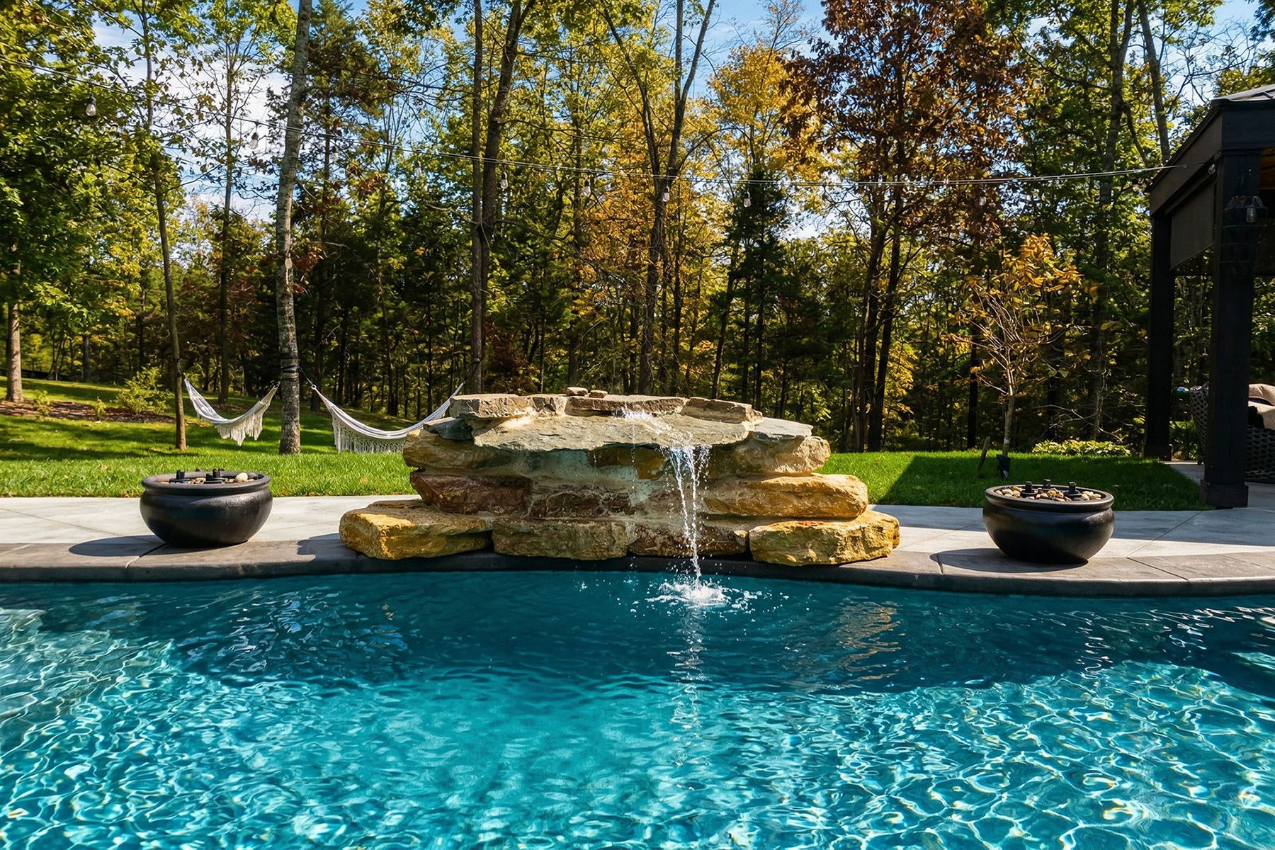 A small rock waterfall feeding into a fiberglass in-ground pool in Crestwood, Kentucky
