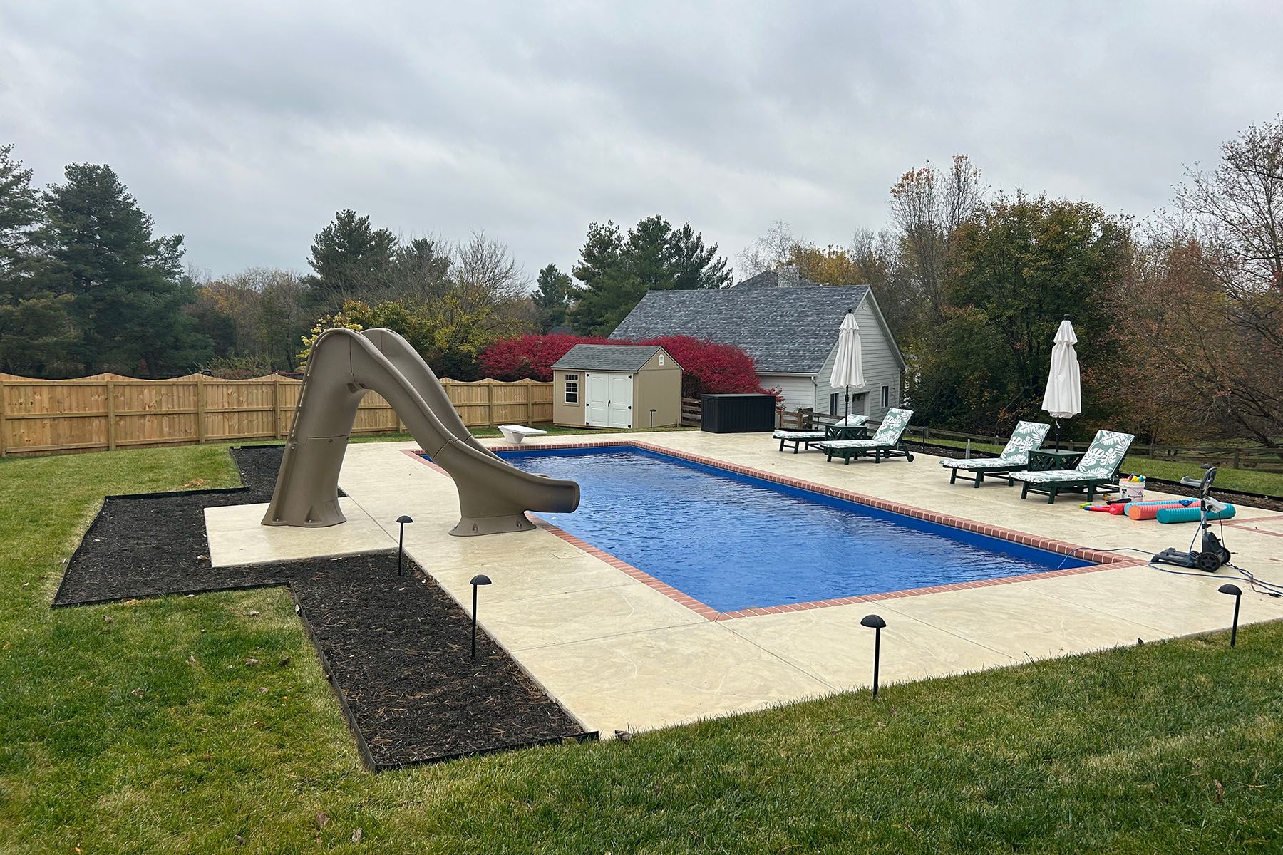 In-ground rectangle fiberglass pool with a slide in Goshen, Kentucky.