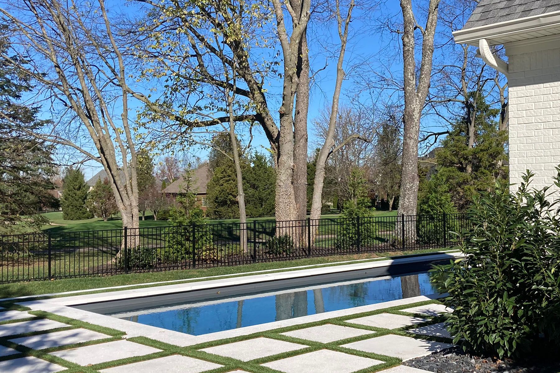 Rectangular in-ground fiberglass swimming pool behind white house in Louisville, Kentucky.