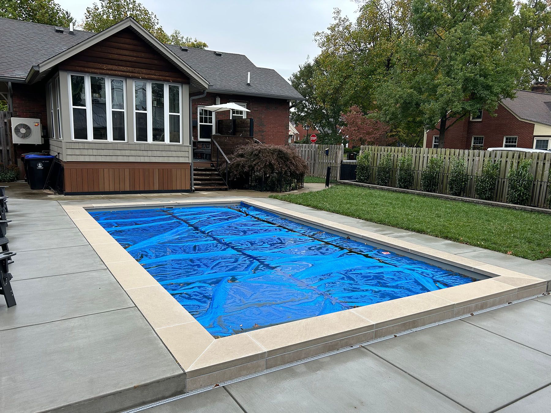 In-ground rectangle fiberglass pool with a blue pool cover in Louisville, Kentucky.
