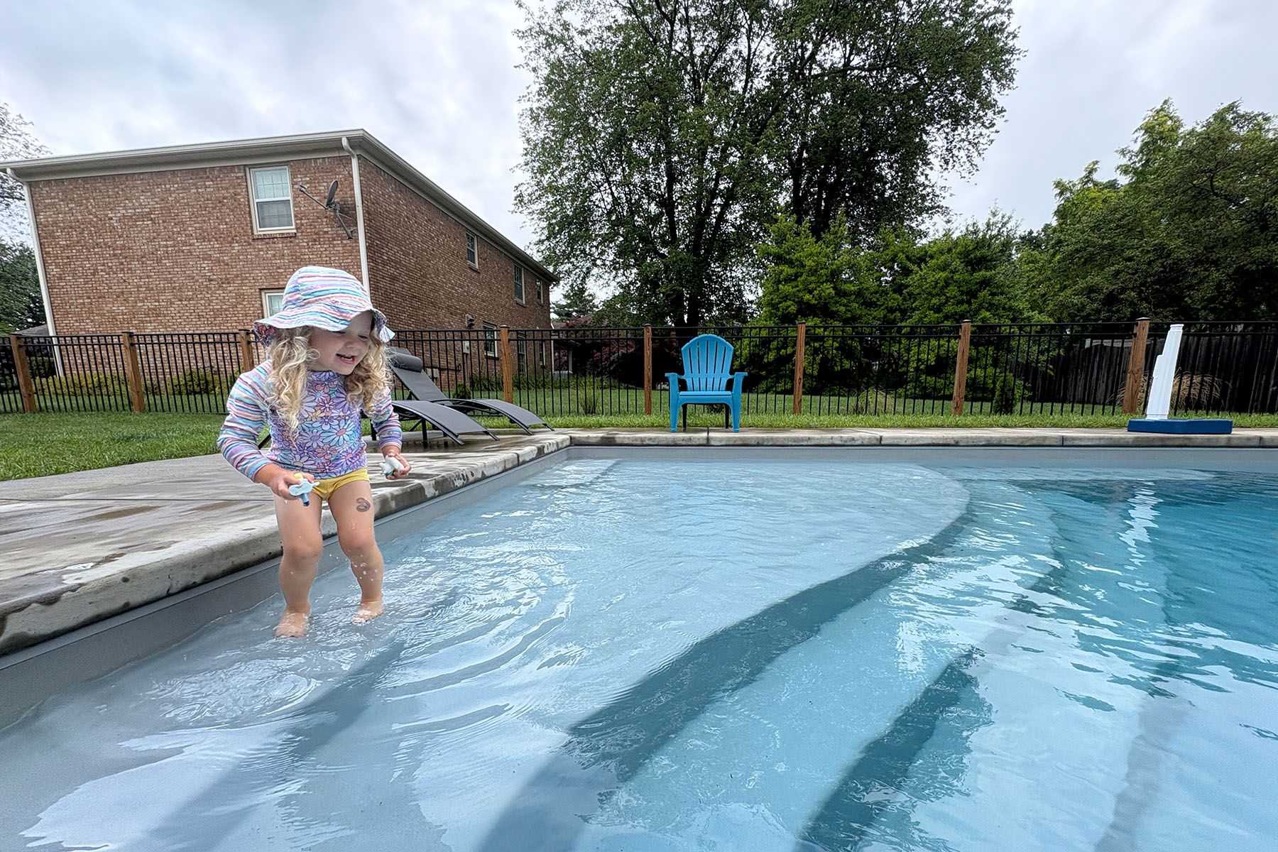 Young girl wading into an in-ground fiberglass pool in Louisville, Kentucky.