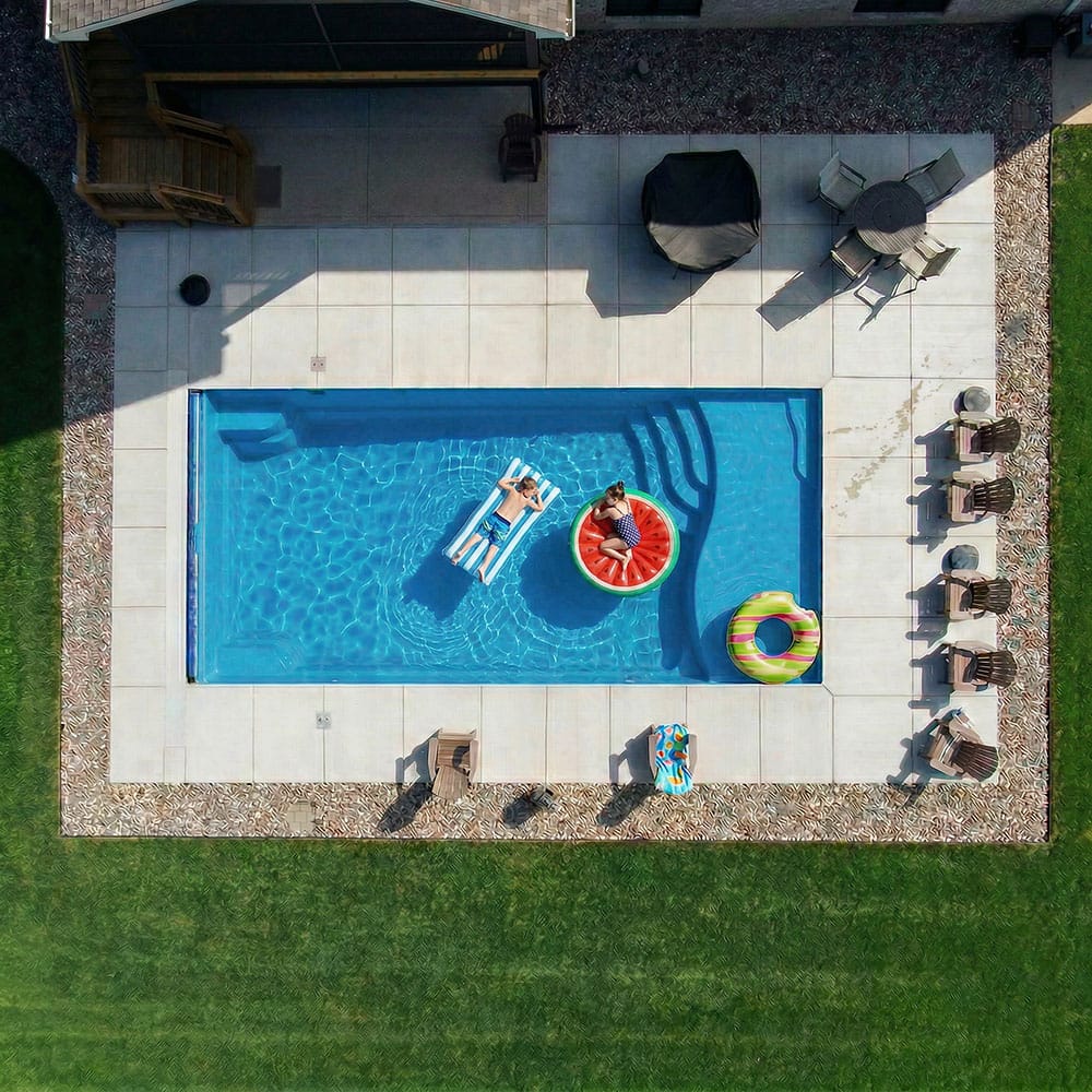 Two children relaxing on floats in a rectangular fiberglass pool in Crestwood, Kentucky