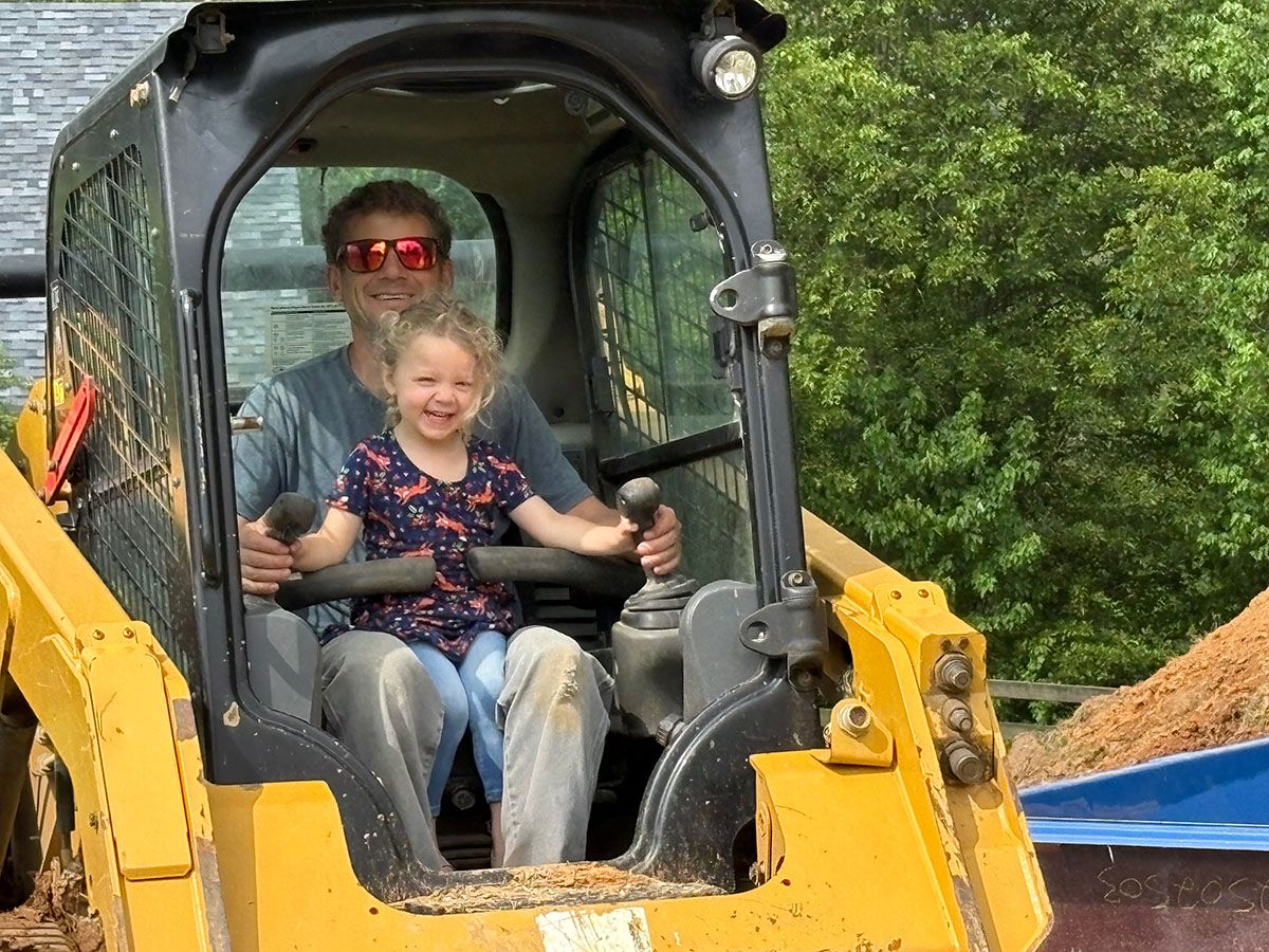 Happy father and daughter getting ready to work with heavy construction equipment.