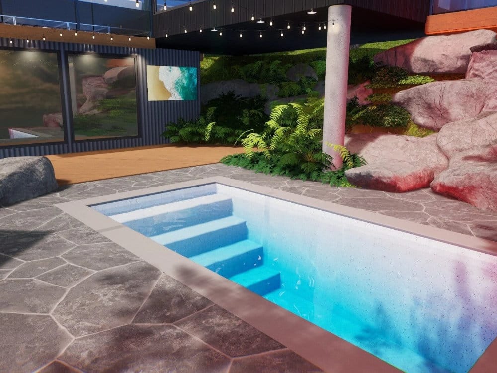 River Pools Fiberglass Plunge Pool with nice concrete patio and large decorative landscape rocks at night with dramatic lighting.