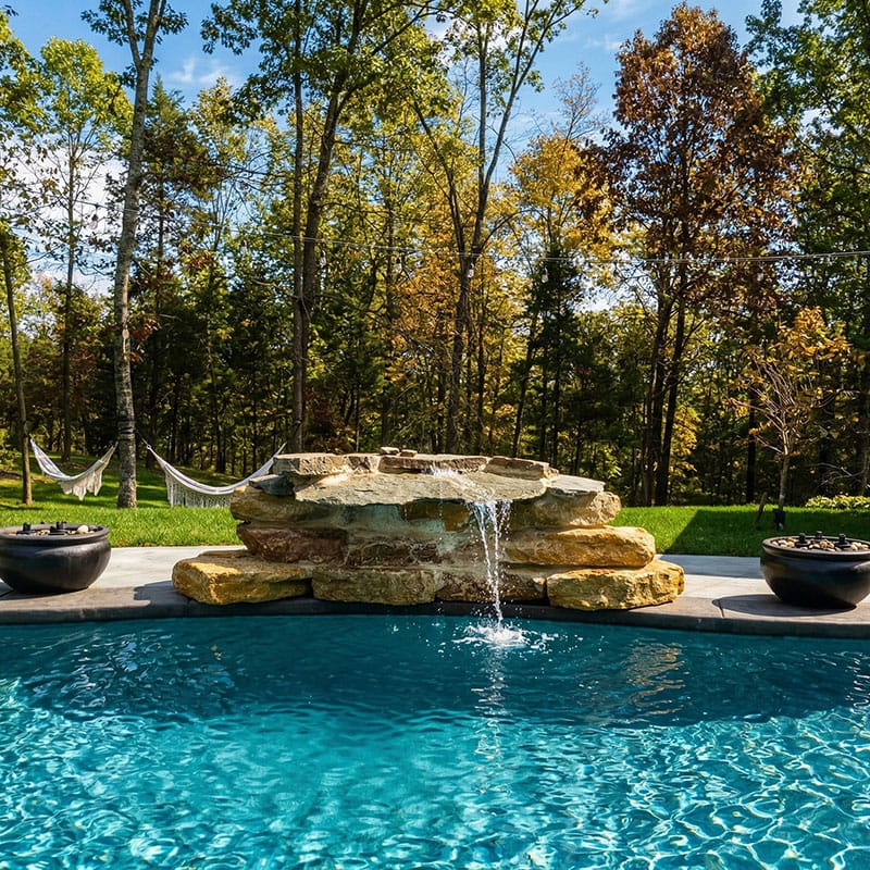 A small rock waterfall feeding into a fiberglass in-ground pool in Crestwood, Kentucky